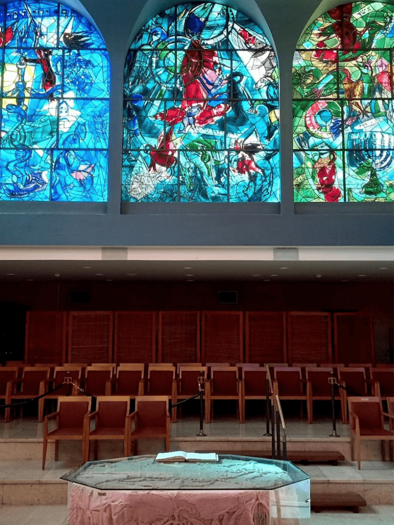 Vibrant stained glass windows depicting biblical scenes in a church sanctuary.
