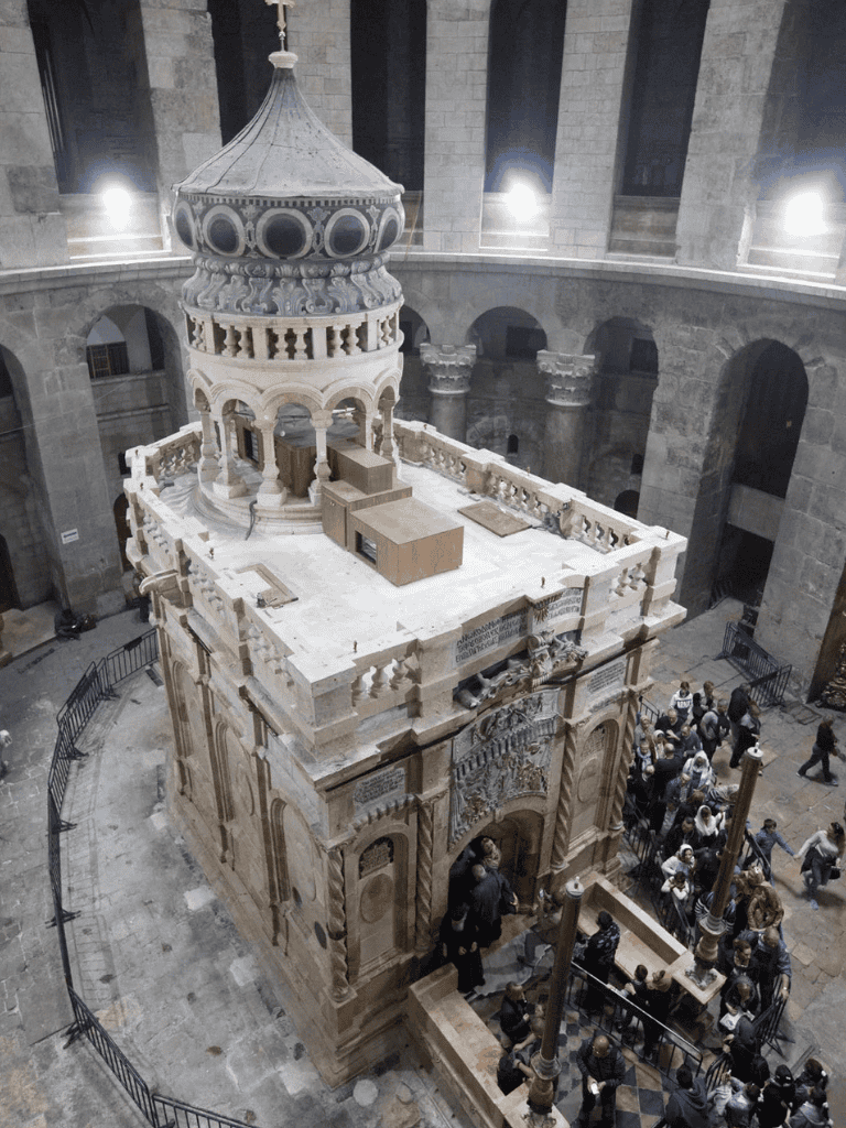 Intricate marble tomb in a historic church, showcasing detailed architecture and a gathering of visitors.