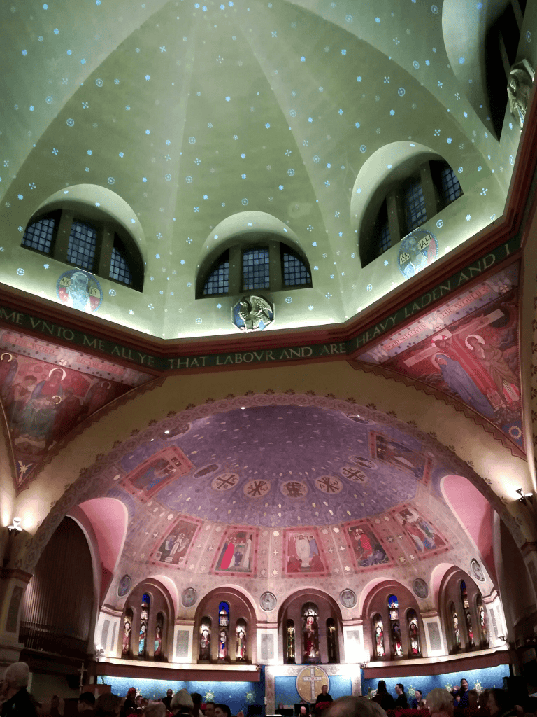 The church interior features a beautifully painted dome with religious murals and stained glass windows, creating a peaceful, sacred atmosphere.