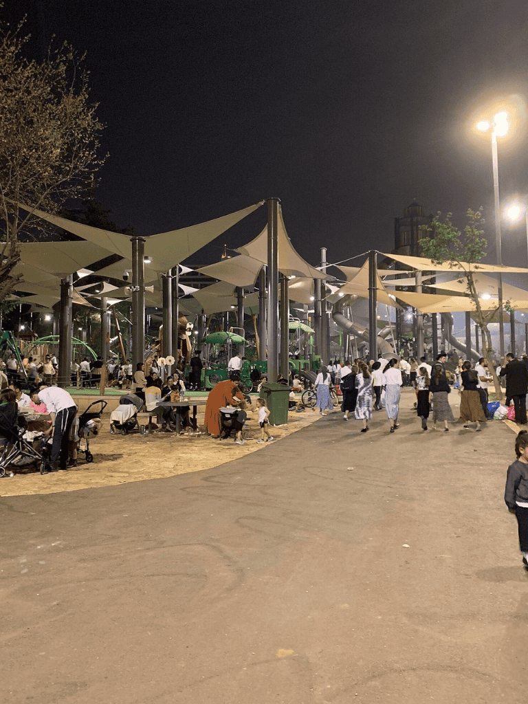 Bright night scene at QuestForDirections outdoor park with children, families, and water slides.