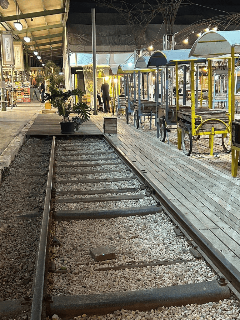 Vintage train track converted into a pedestrian walkway with seating and shops nearby.