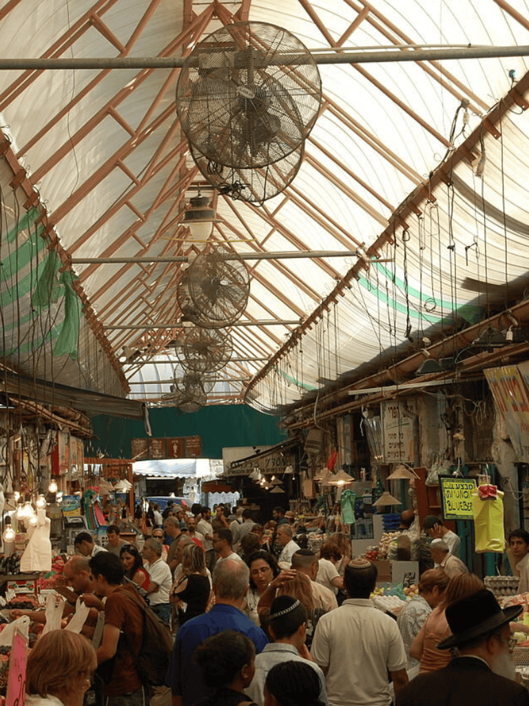 Crowded marketplace in an open-air market with vendors and shoppers, vibrant and bustling atmosphere.