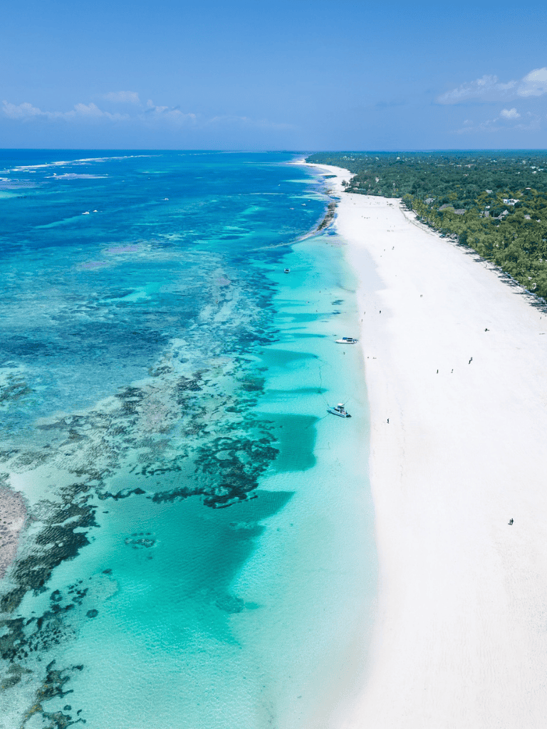 Pristine coastal beach with clear turquoise waters and white sand shoreline, ideal for relaxation and water activities.