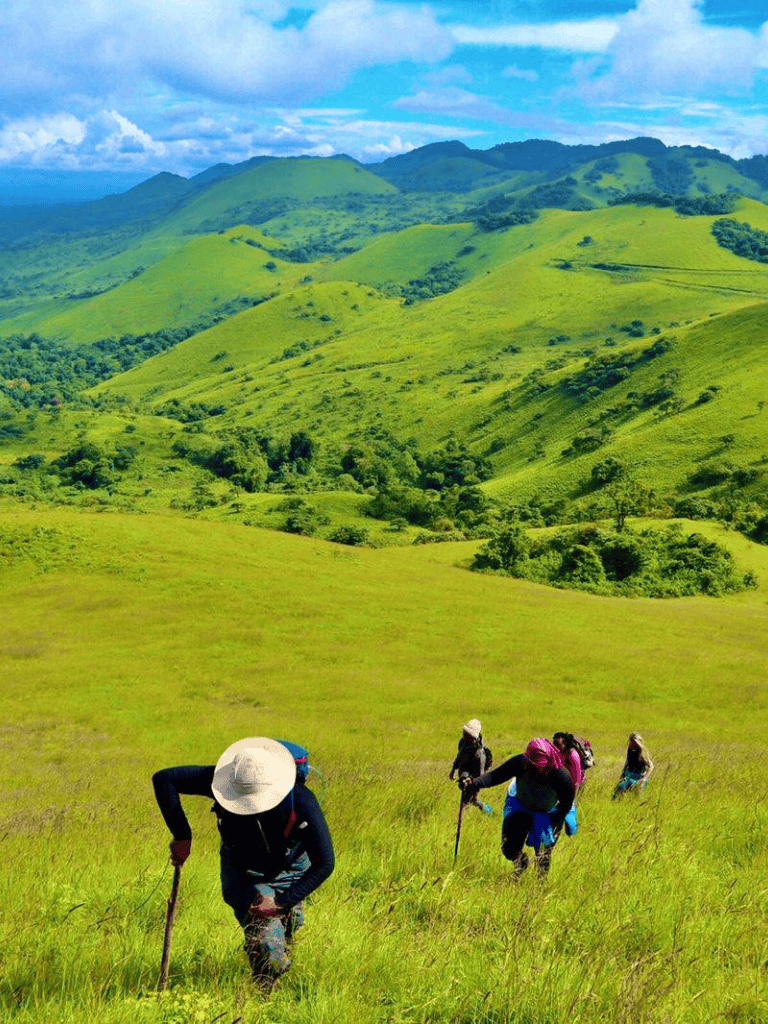 Hiking in lush green hills with mountain backdrop, colorful outdoor adventure scene.