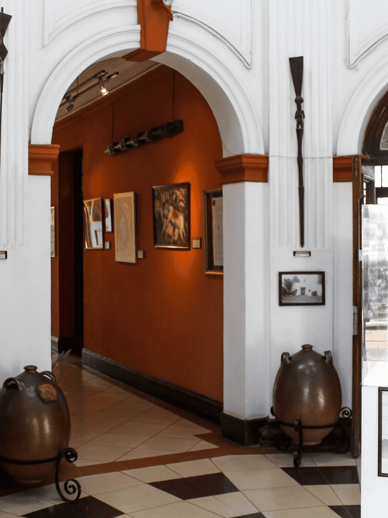 Museum interior with framed artwork and decorative pottery, showcasing artistic and historical exhibits.