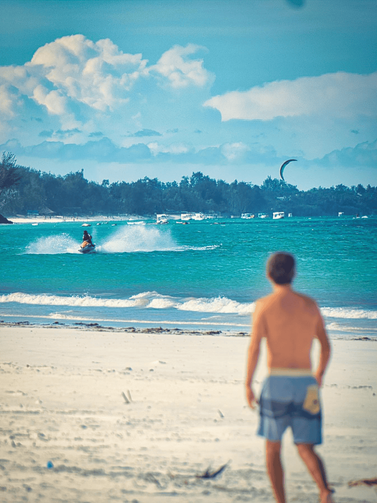Relaxing beach scene with a person watching kite surfers and a scenic ocean view.