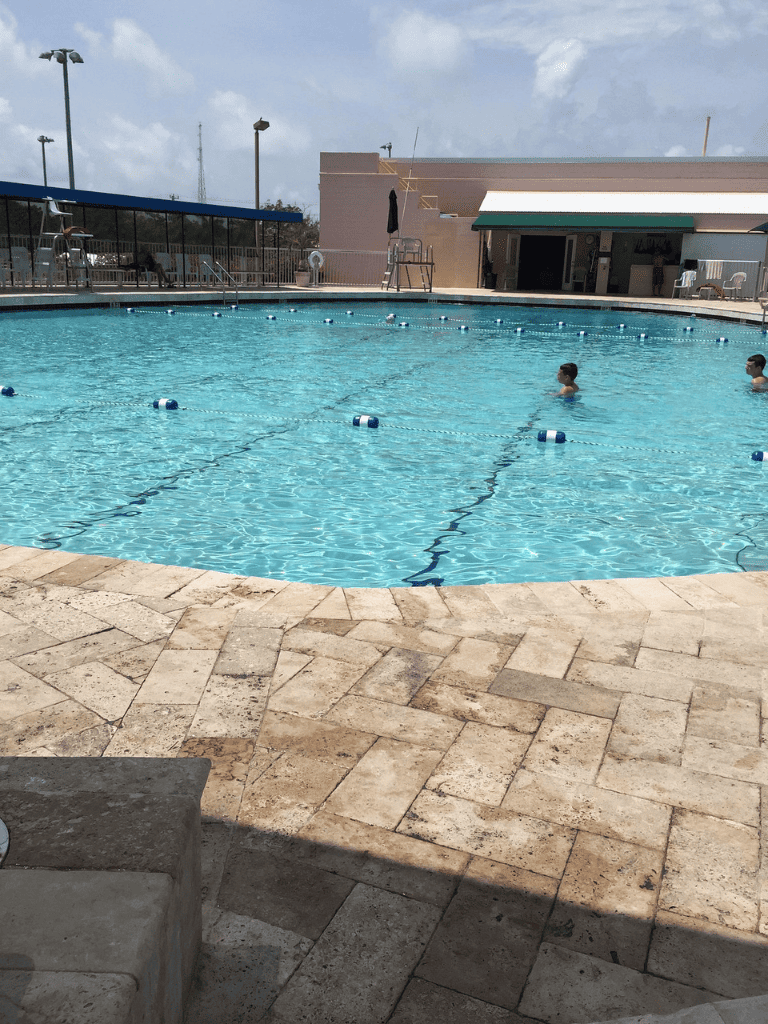 Pool with swim lanes and people relaxing, located at QuestForDirections.