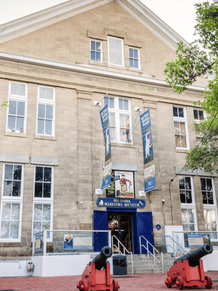 Historic maritime museum building with cannons at entrance, featuring flags and maritime exhibits, for marine history education.