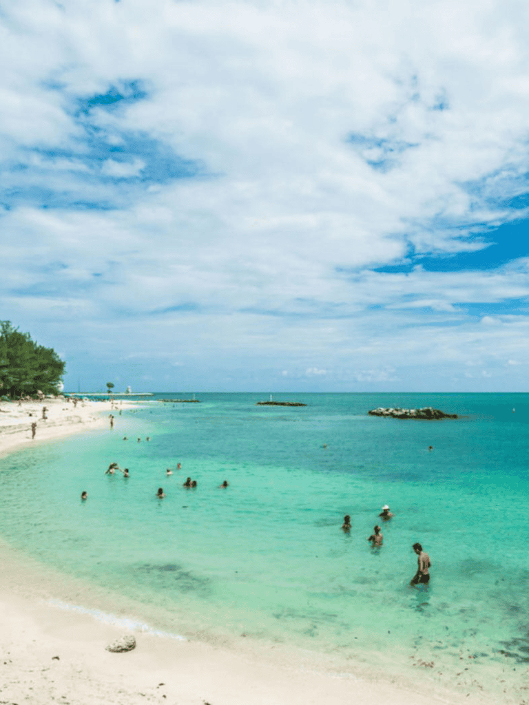 Relaxing beach with turquoise waters and swimmers, perfect for travel and vacation planning.