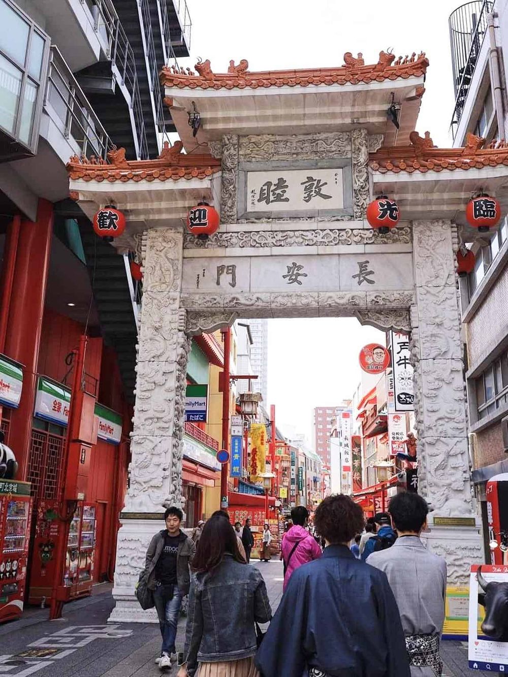 Vibrant Chinatown street with traditional archway entrance, colorful signage, and bustling crowd, guided tour, local cuisine, cultural experience.