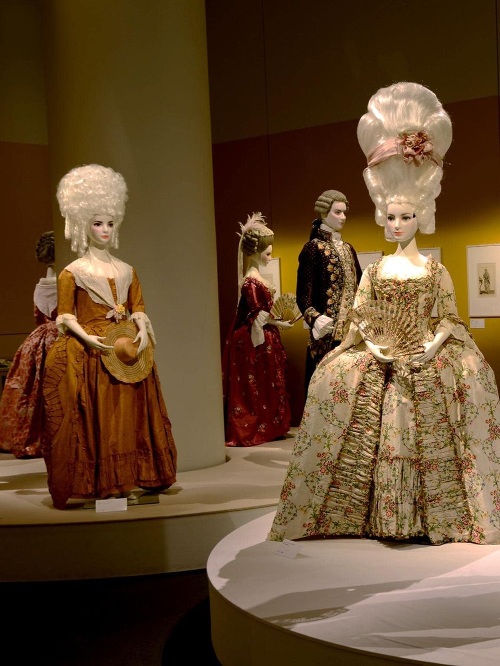 Vintage rococo costumes on mannequins at a fashion exhibit, showcasing historical 18th-century European clothing styles.