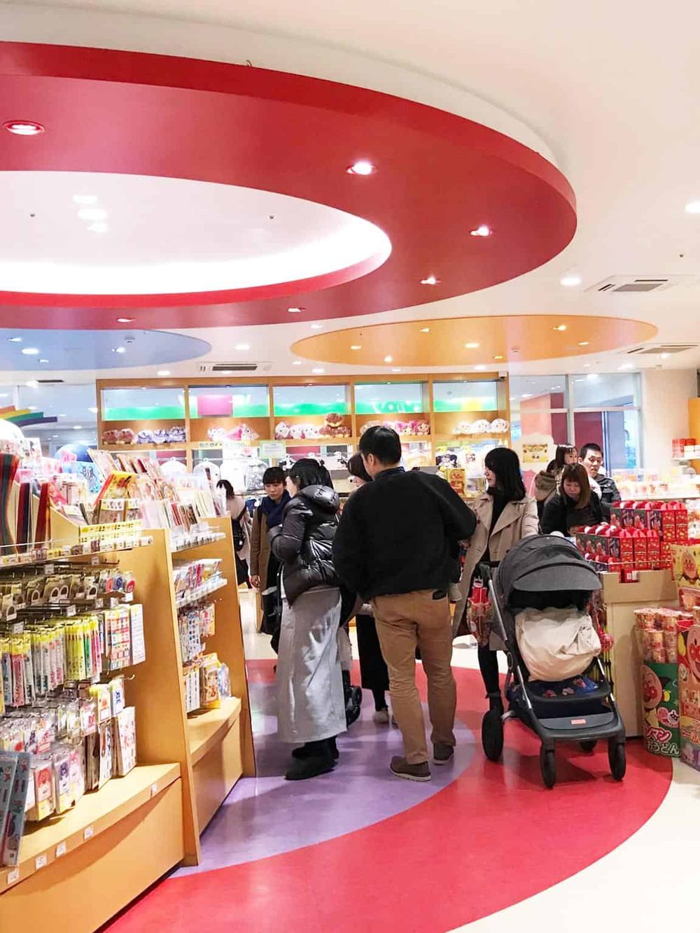 Bright indoor toy and gift store with shoppers browsing colorful merchandise.