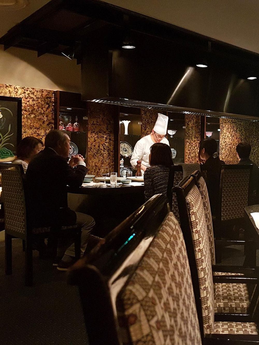 Elegant restaurant dining with a chef preparing meals for guests, emphasizing fine dining experiences.