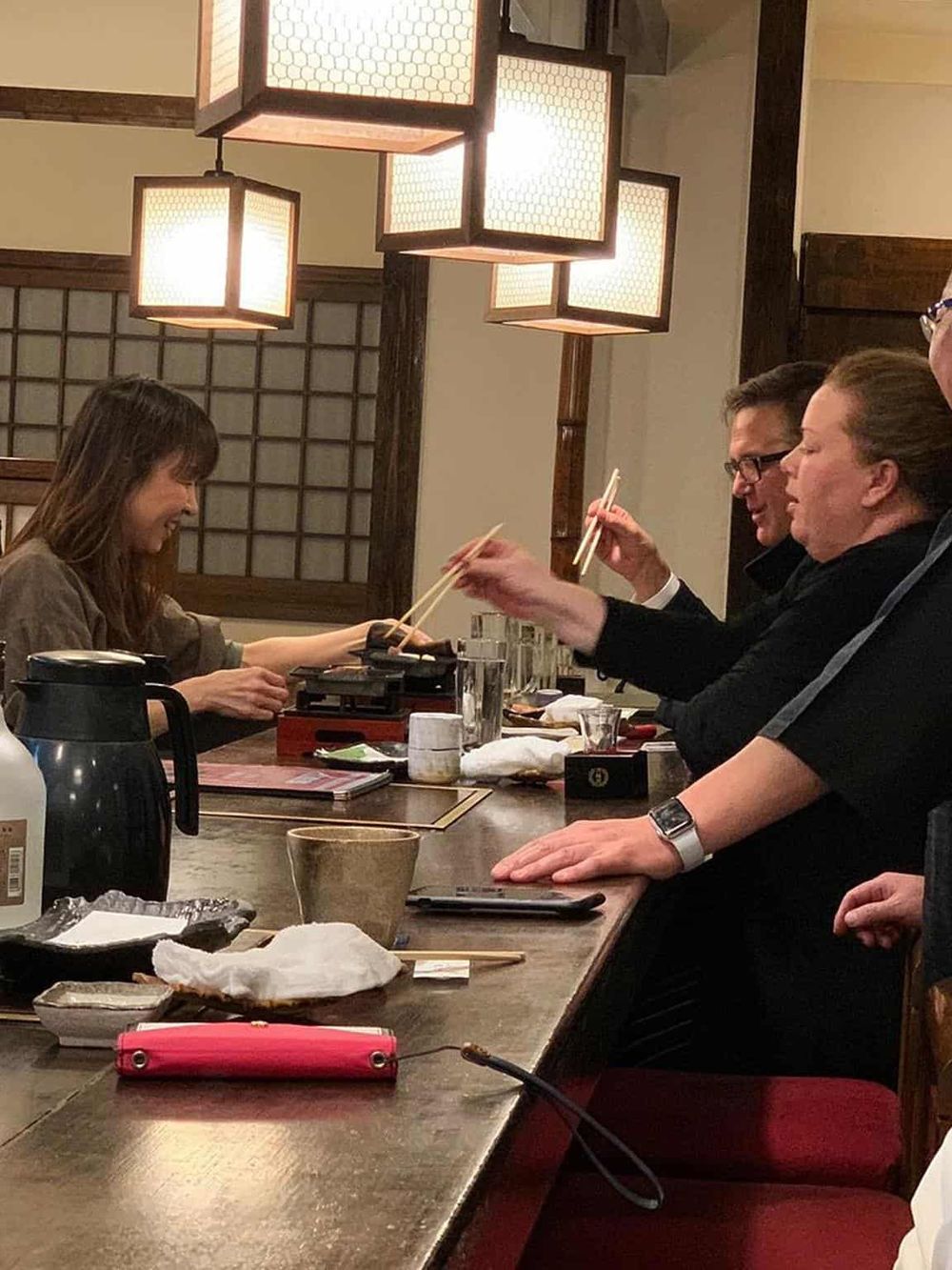 A cozy Japanese restaurant scene with friends sharing a meal, enjoying sushi and chopsticks in a traditional ambiance.