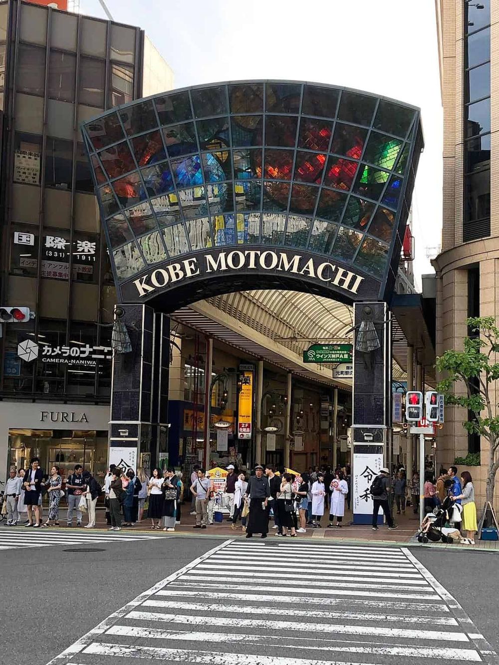 Crowd waiting at Kobe Motomachi shopping street entrance in Japan, vibrant urban retail hub.