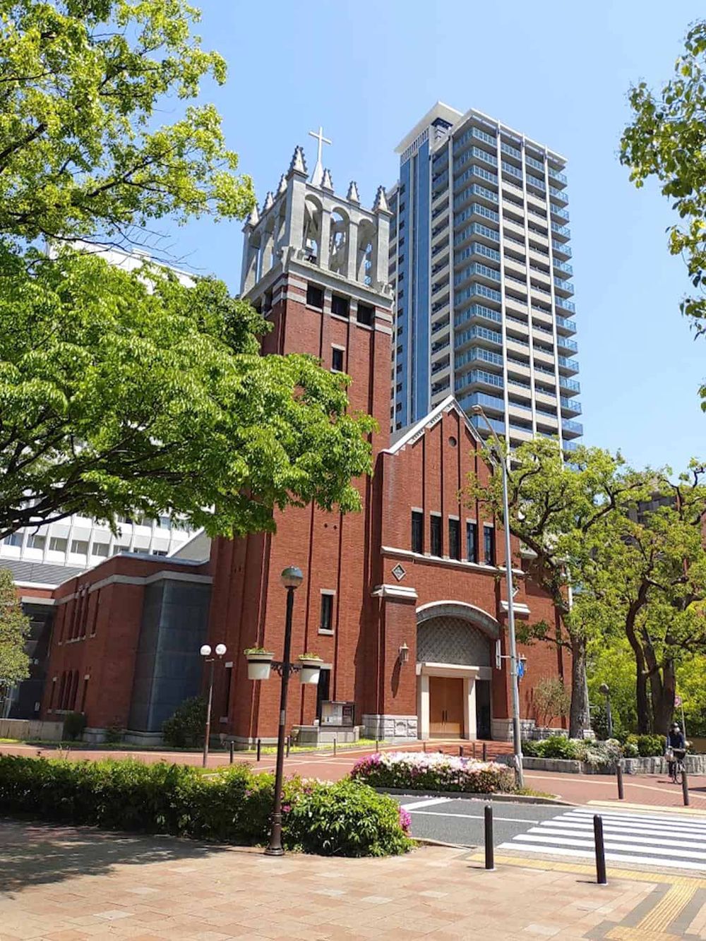 Colorful city scene featuring a historic church and modern high-rise building under clear blue sky.