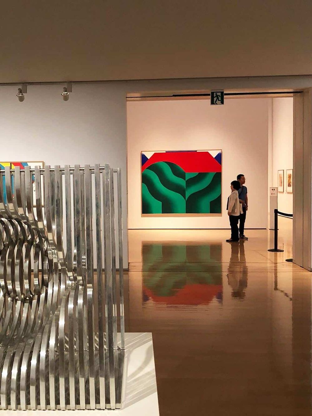 Colorful abstract art at museum gallery with visitors admiring artwork.