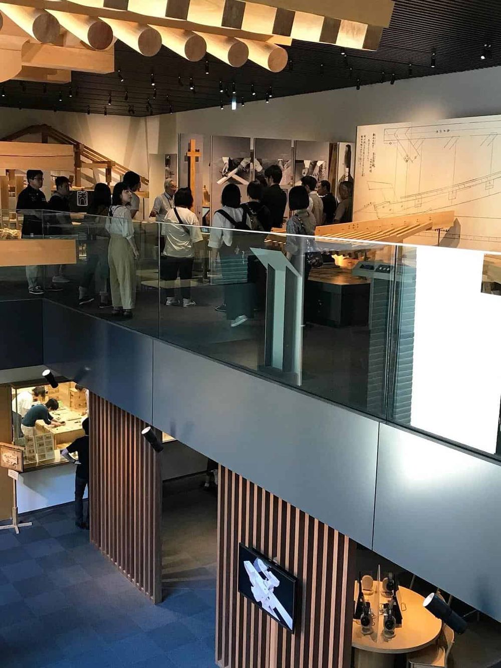 Modern museum exhibit showcasing woodworking and construction models, with visitors engaging in educational activities.