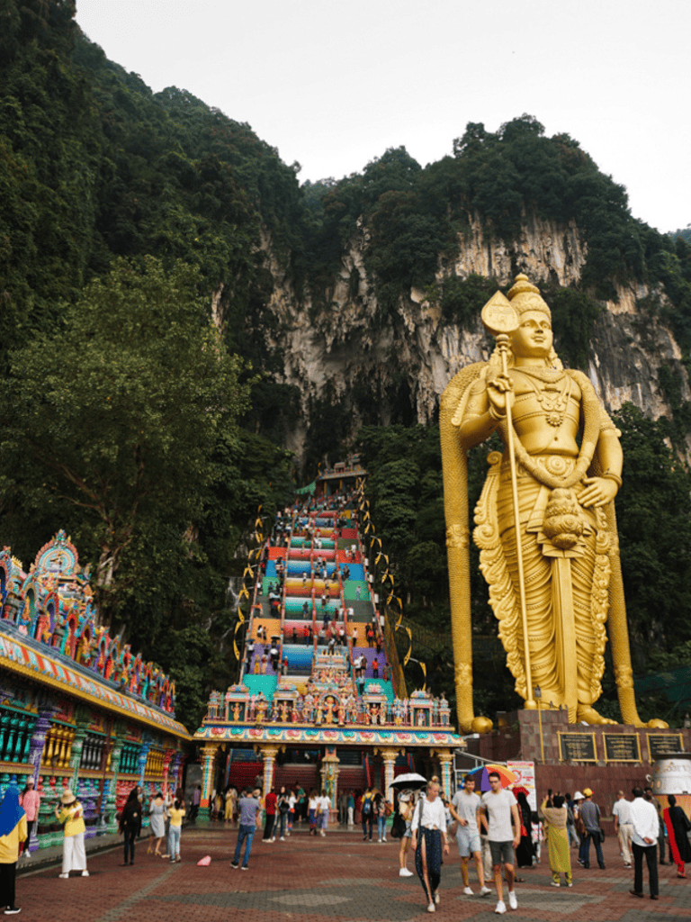 Majestic Batu Caves Hindu temple with towering golden statue and vibrant stairway.