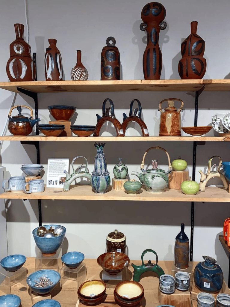 Colorful pottery and ceramic art pieces on wooden shelves at QuestForDirections.