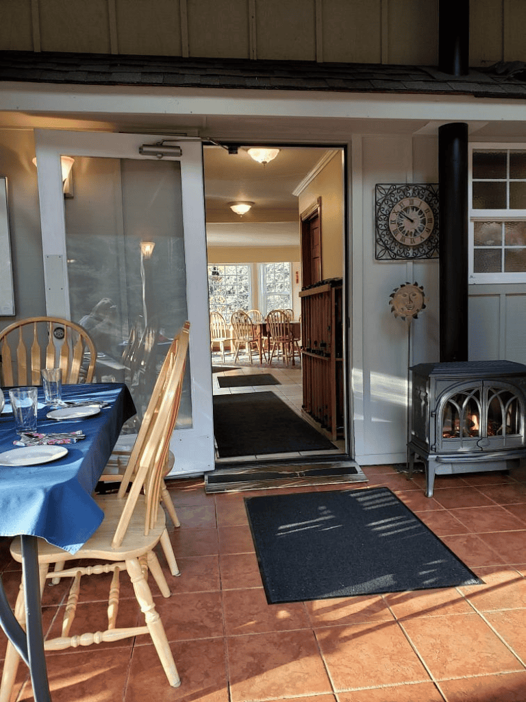 Cozy indoor dining space with a stove, wooden chairs, and a scenic view through the windows.