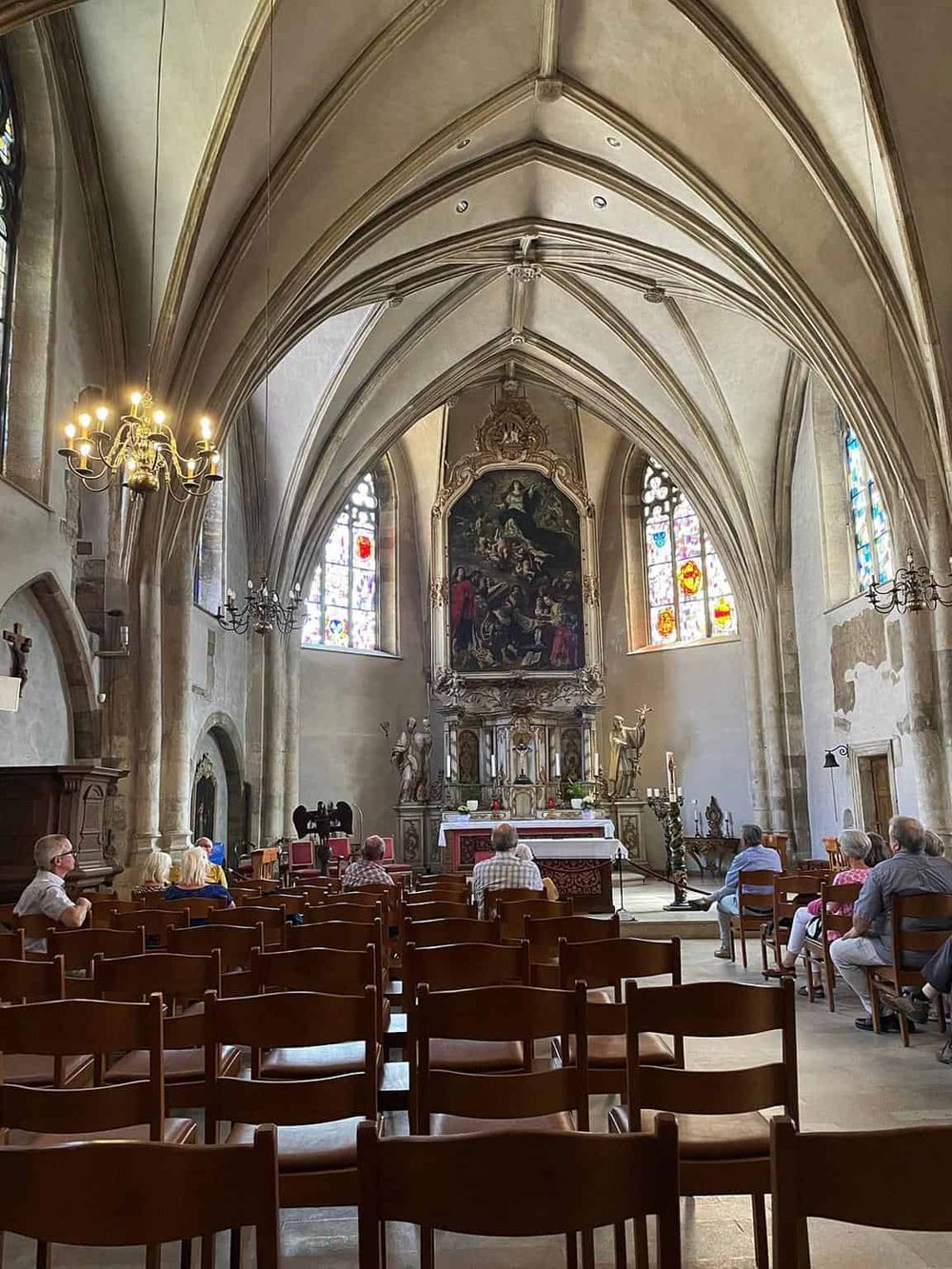 Quiet church interior with stained glass windows and ornate altar, welcoming visitors for reflection and prayer.
