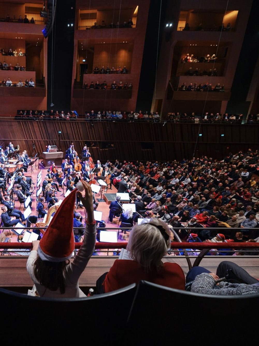 Vibrant symphony concert in concert hall with orchestra and audience enjoyment, festive holiday atmosphere.