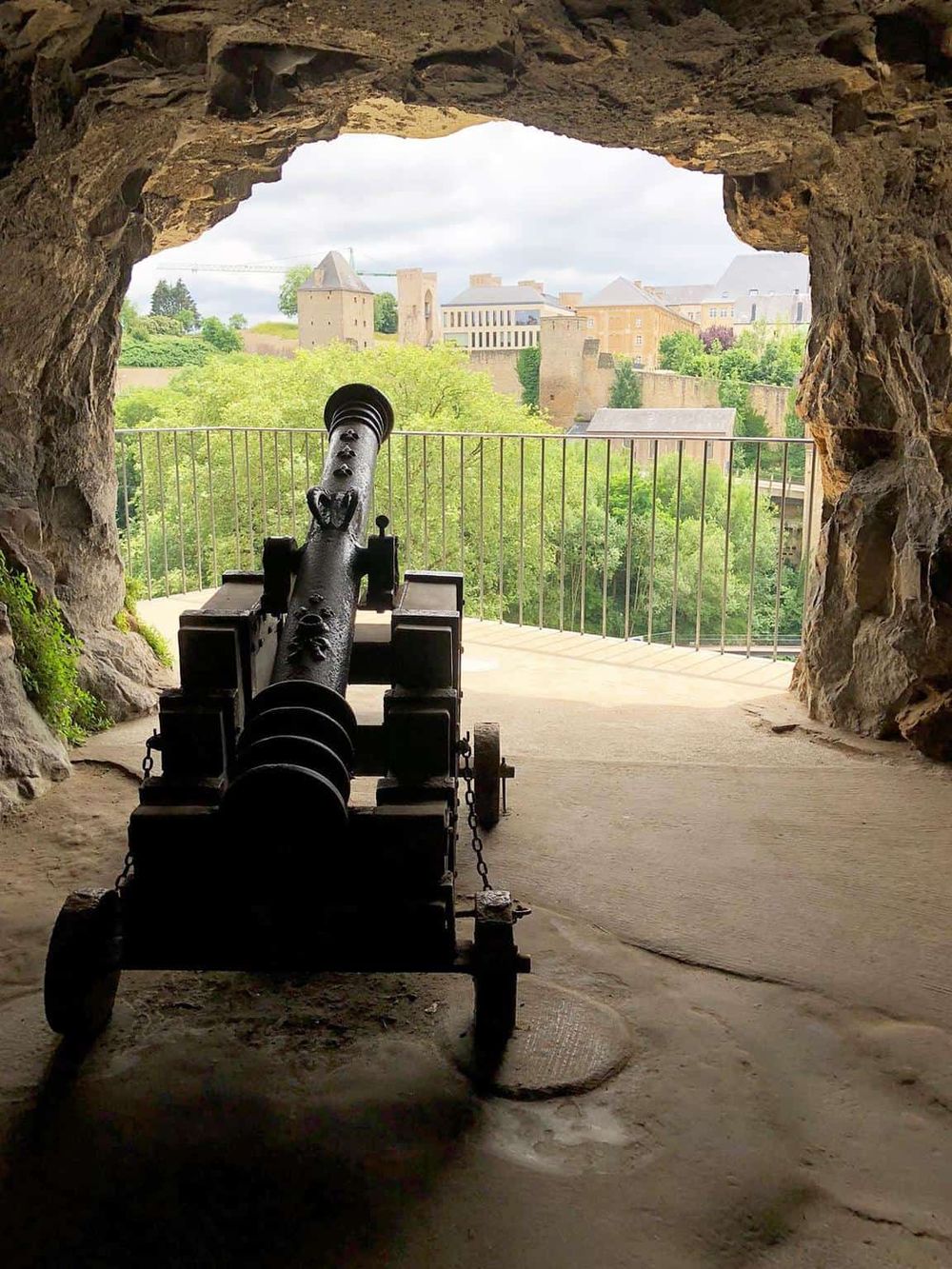 Ancient cannon overlooking Luxembourg City from a castle cave, historical fortress, and scenic view.