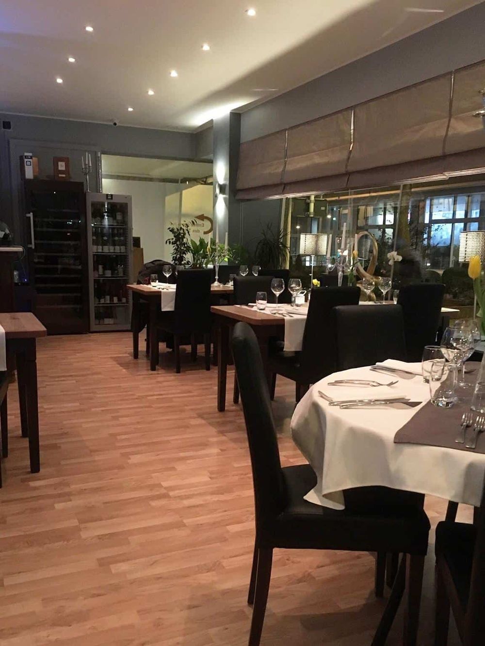Modern restaurant interior with elegant dining setup, black chairs, white tablecloths, and ambient lighting, perfect for dining experiences.