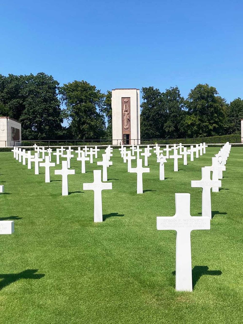 White crosses memorial at the World War II Memorial in Washington, D.C., with a statue in the background.