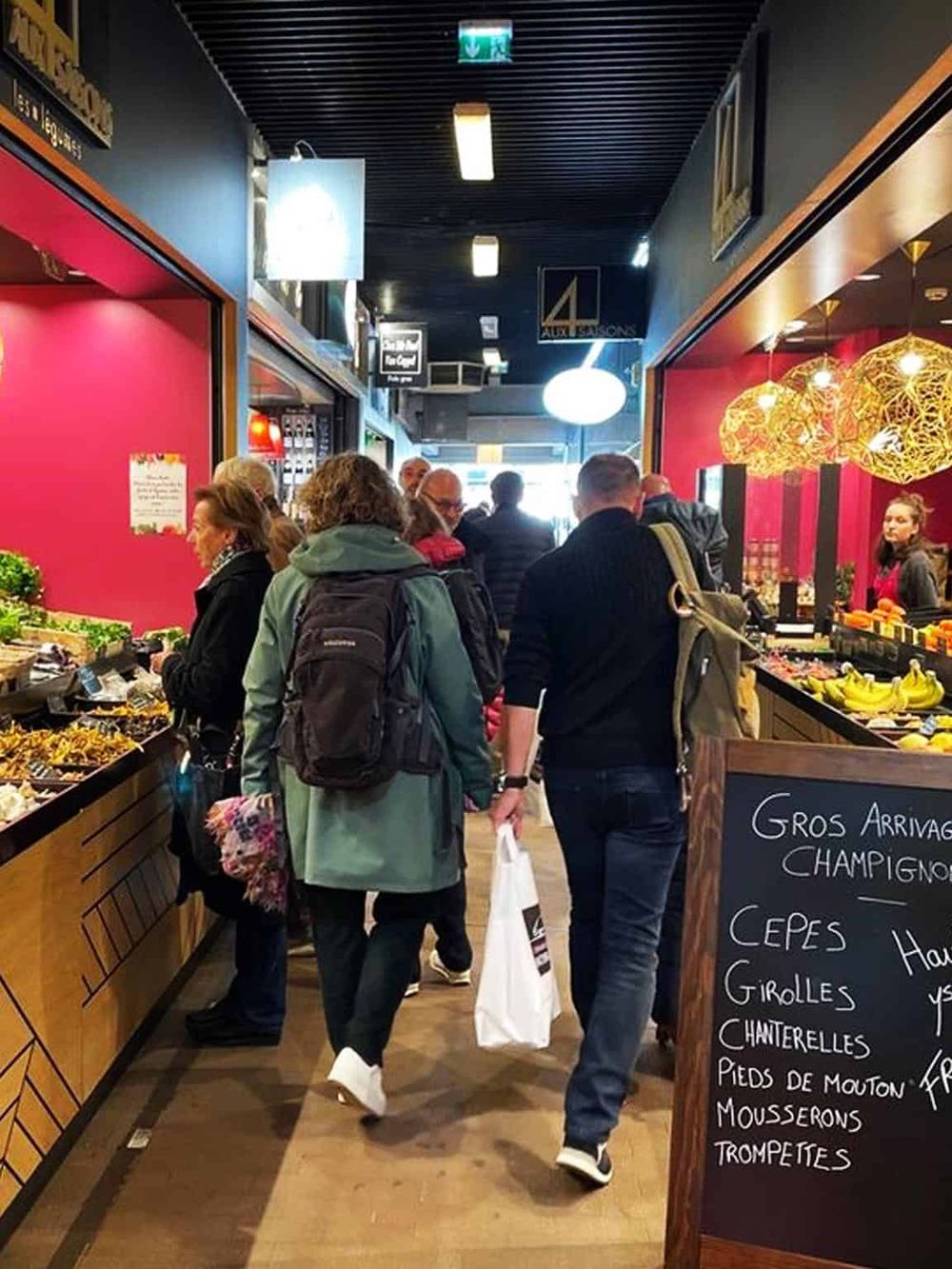 Fresh produce shopping at a bustling indoor market with vibrant color decor and a variety of fruits and vegetables.
