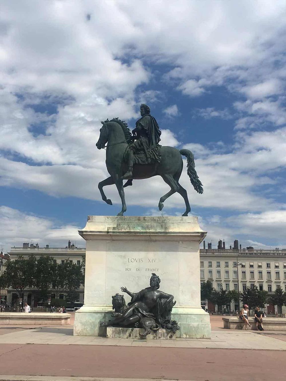 Bronze equestrian statue of Louis XIV in Paris with clouds in the sky.