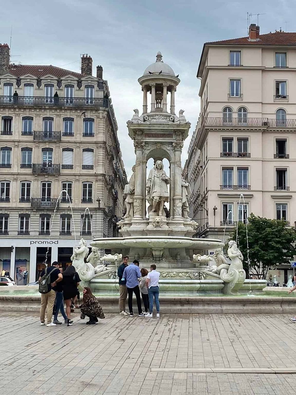 Elegant marble fountain with classical sculptures in a European city square, popular tourist attraction.