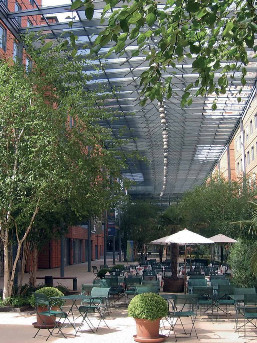 Outdoor dining area with greenery underneath a modern canopy in downtown.