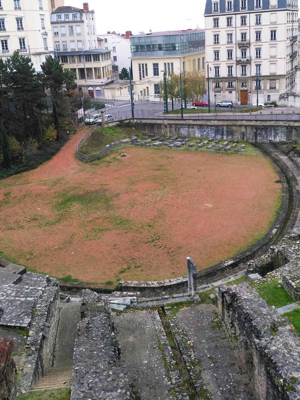 Ancient amphitheater ruins in an urban setting, showcasing archaeological site preservation and historical architecture.