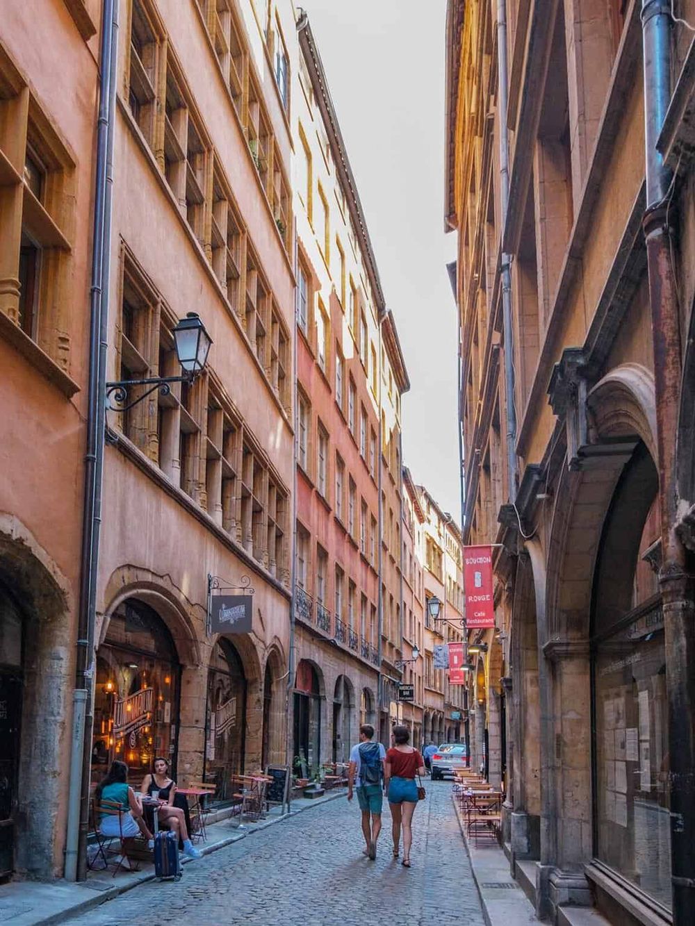 Charming narrow European street with historic buildings, cafes, and cobblestone pavement ideal for travel and navigation.