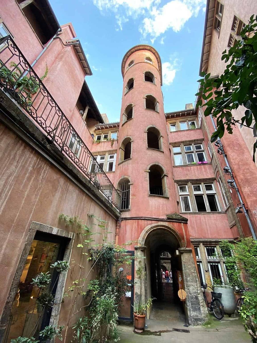Pink historic residential building with tower and archway, located in a European city.