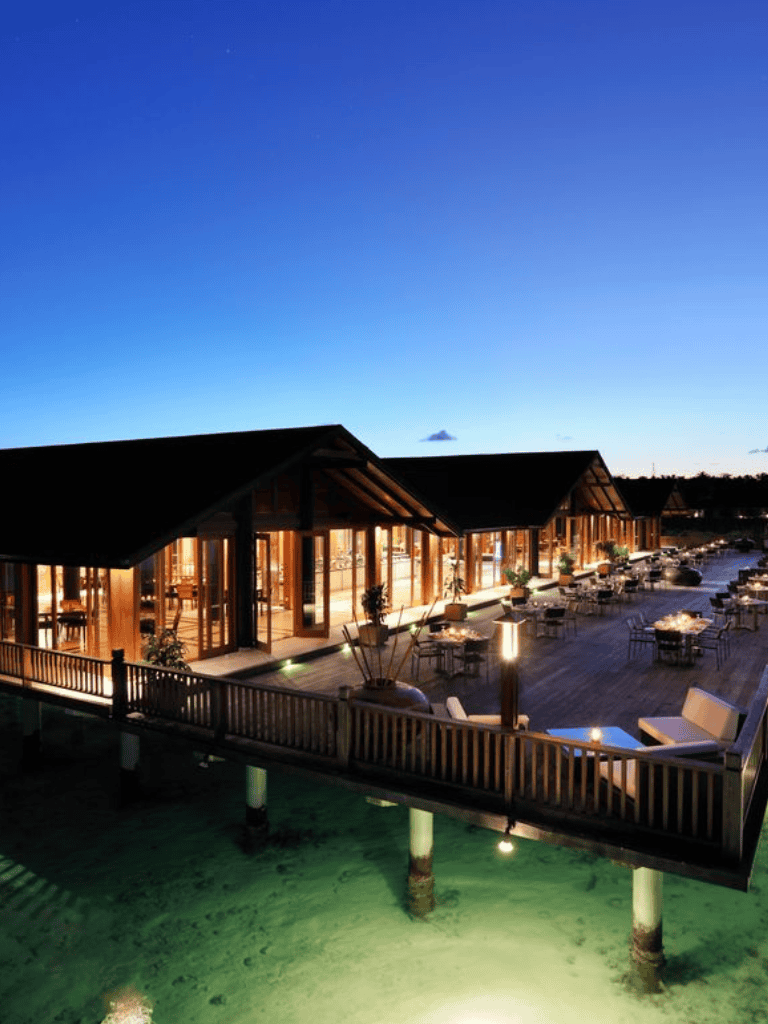 Luxurious lakeside restaurant with waterfront views and outdoor seating at dusk.