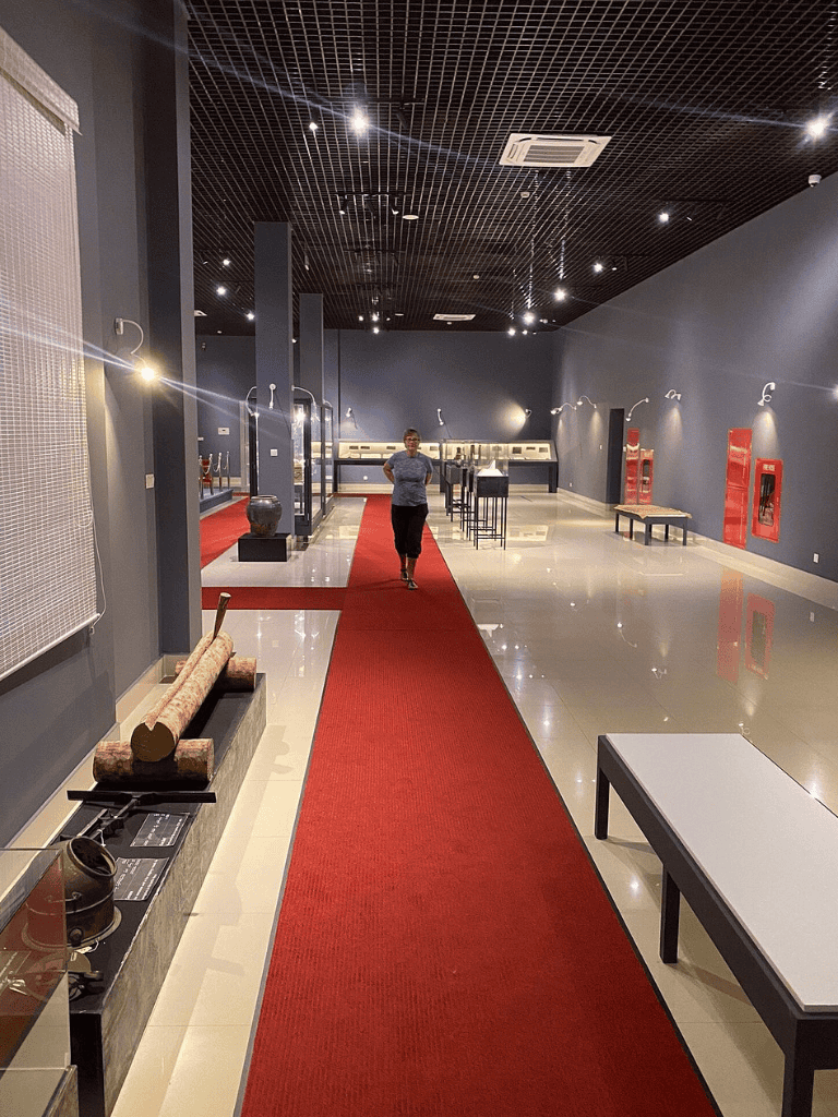 Historic artifacts display in a modern museum exhibit space, featuring a red carpet, sculptures, and informational panels.