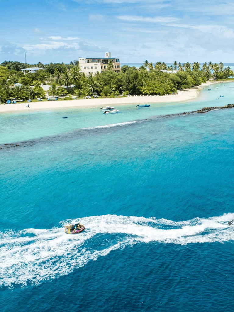 Relaxing Caribbean beach with boats and lush greenery at QuestForDirections destination.