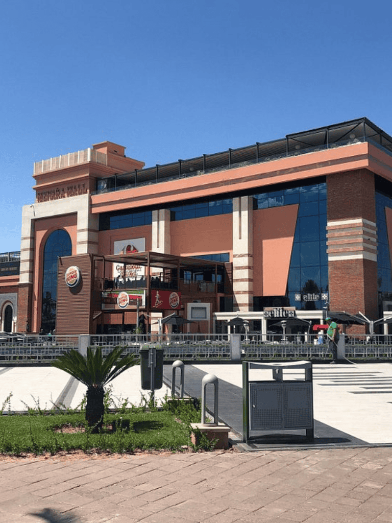 Burger restaurant exterior in shopping mall, modern architecture and outdoor seating area.