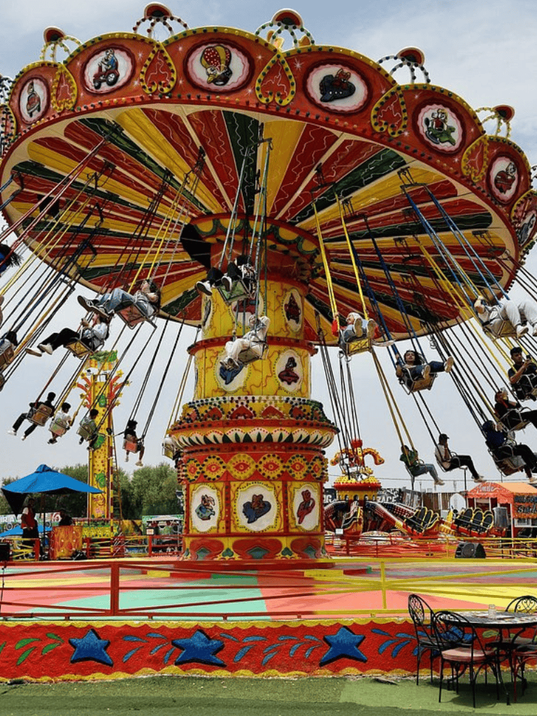Colorful amusement park swing ride with children enjoying the fun atmosphere.