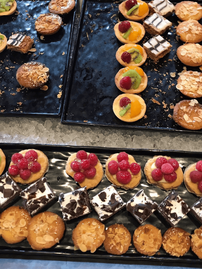 Delicious assorted cookies and pastries for catering or events, featuring fruit, chocolate, and almond toppings.