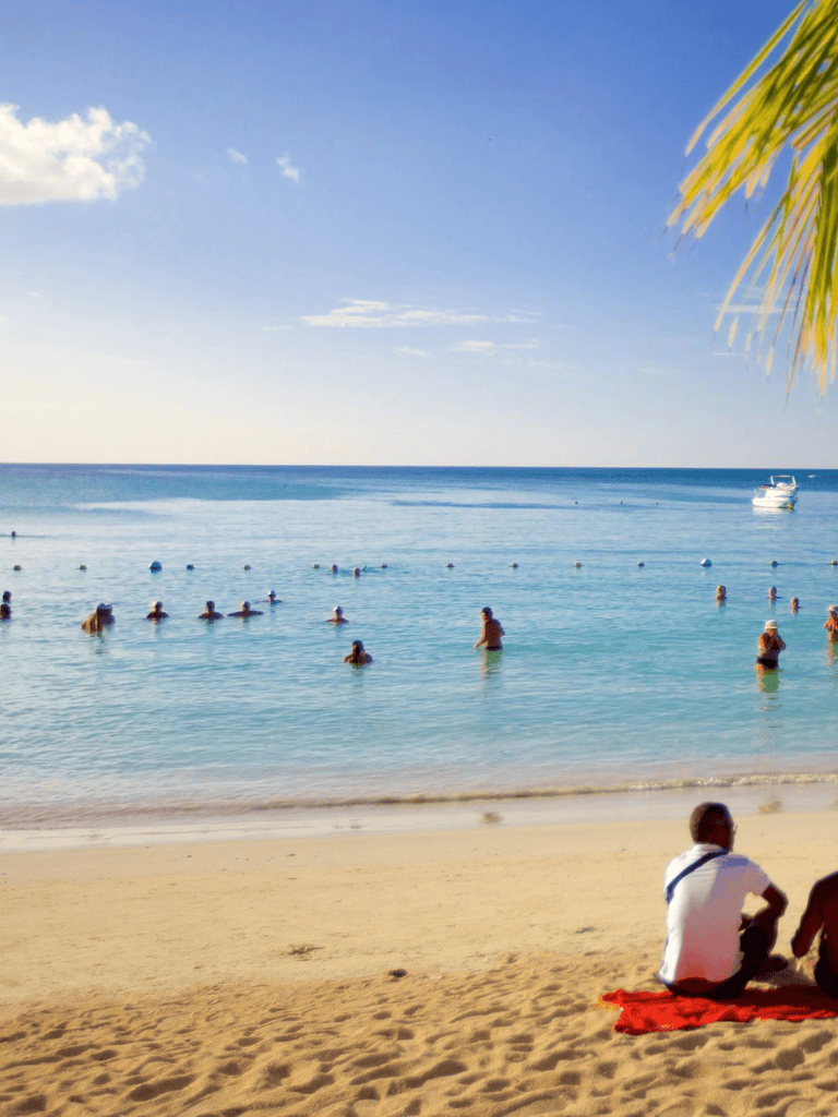 Beach with people swimming and relaxing, sunny day at QuestForDirections.