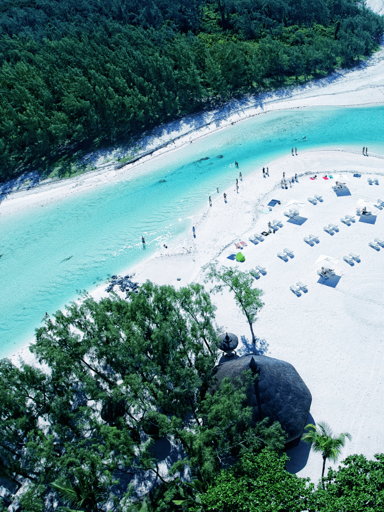 Turquoise river flowing through white sandy beach with trees and loungers, vacation paradise, QuestForDirections.
