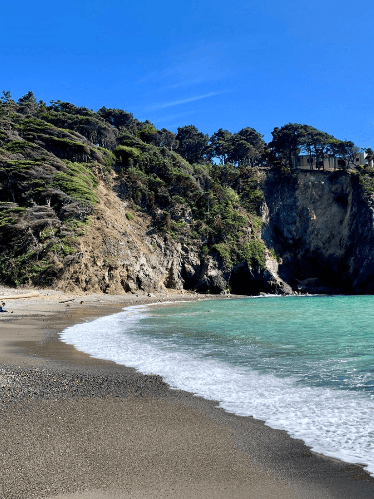 Serene beach with cliffs and lush greenery, perfect for exploring coastal adventures.