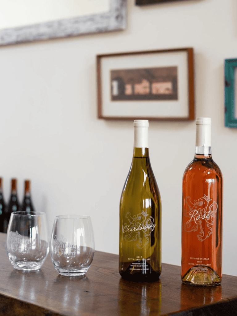 Wine bottles with custom labels and glasses on a wooden table.