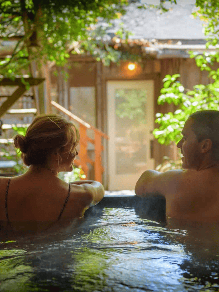 Relaxing couple enjoying warm bath in private outdoor hot tub surrounded by greenery, perfect for relaxing and rejuvenating.