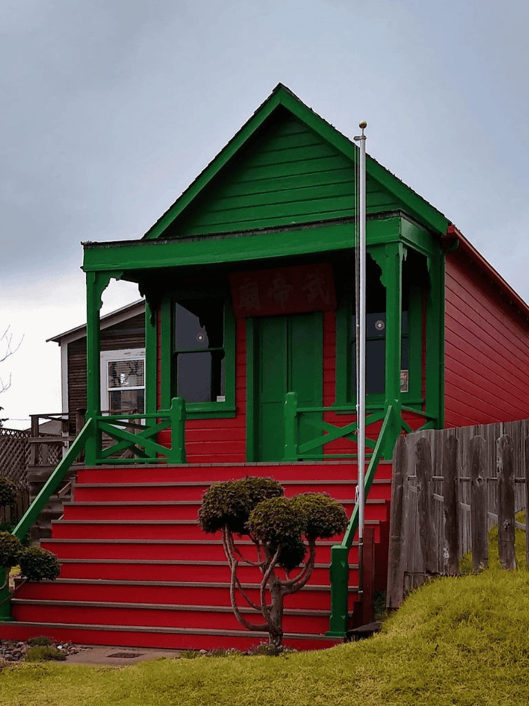 Colorful tiny house with stairs and green trim, perfect for unique homes or escapes.