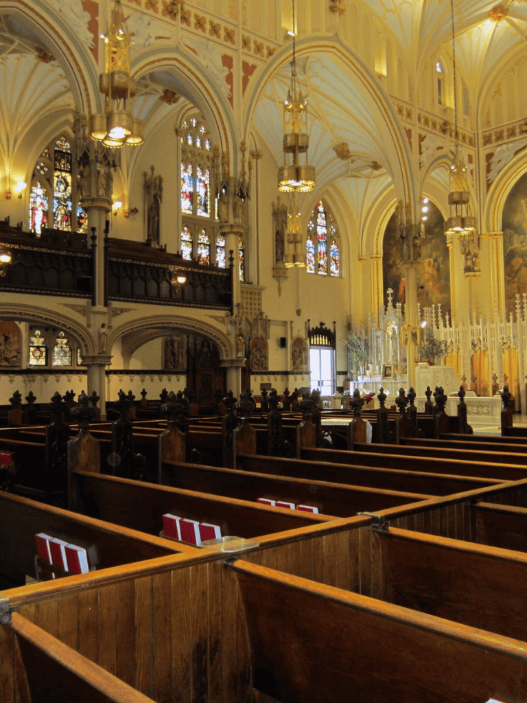 Elegant church interior with stained glass windows, ornate chandeliers, and wooden pews for spiritual guidance.